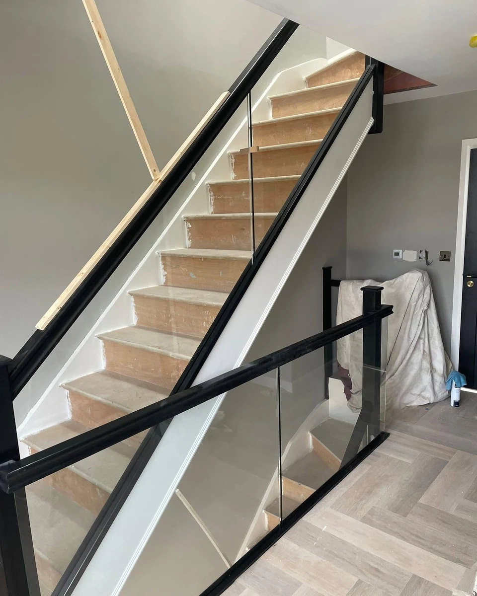 staircase-glass-balustrade-black-frame-herringbone-reigate-reigate-glass-balustrades Frameless glass balustrade with black frame on herringbone floor staircase, Reigate