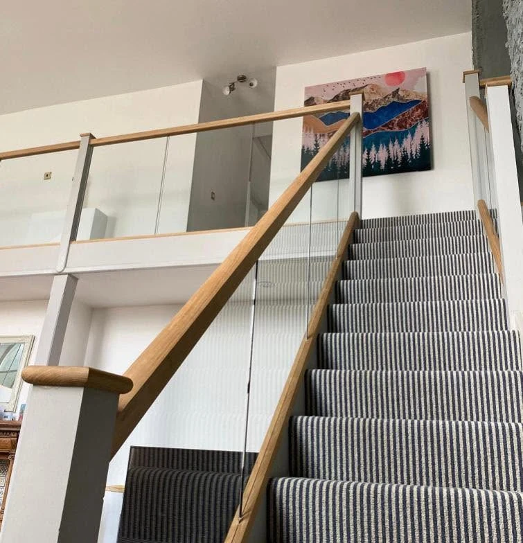 staircase-glass-balustrade-oak-rail-striped-runner-reigate-reigate-glass-balustrades Glass balustrade with oak rail on striped runner staircase, Reigate